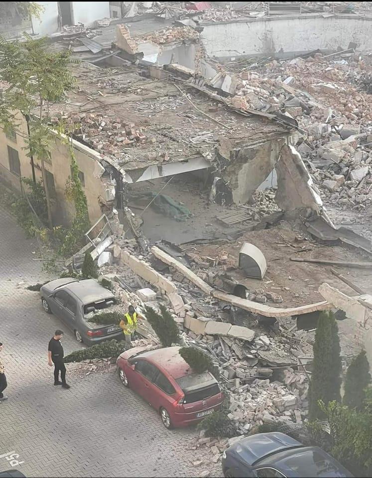 Zidul unui fost supermarket, demolat peste mașini parcate. Șantierul face loc unui bloc turn