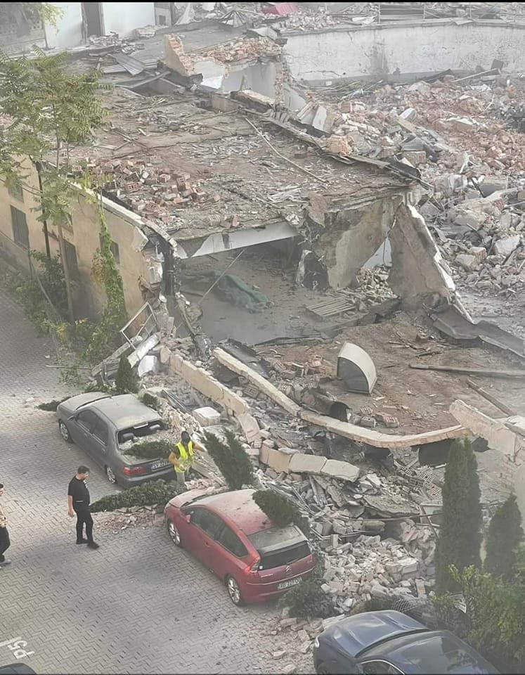 Zidul unui fost supermarket, demolat peste mașini parcate. Șantierul face loc unui bloc turn
