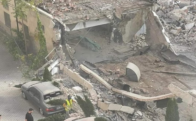 Zidul unui fost supermarket, demolat peste mașini parcate. Șantierul face loc unui bloc turn
