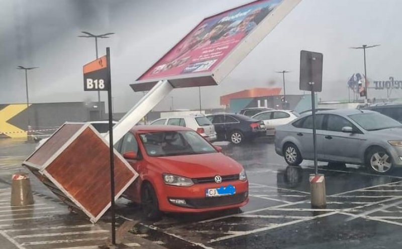 Panou publicitar CĂZUT peste mașina unui clujean în parcarea unui mall