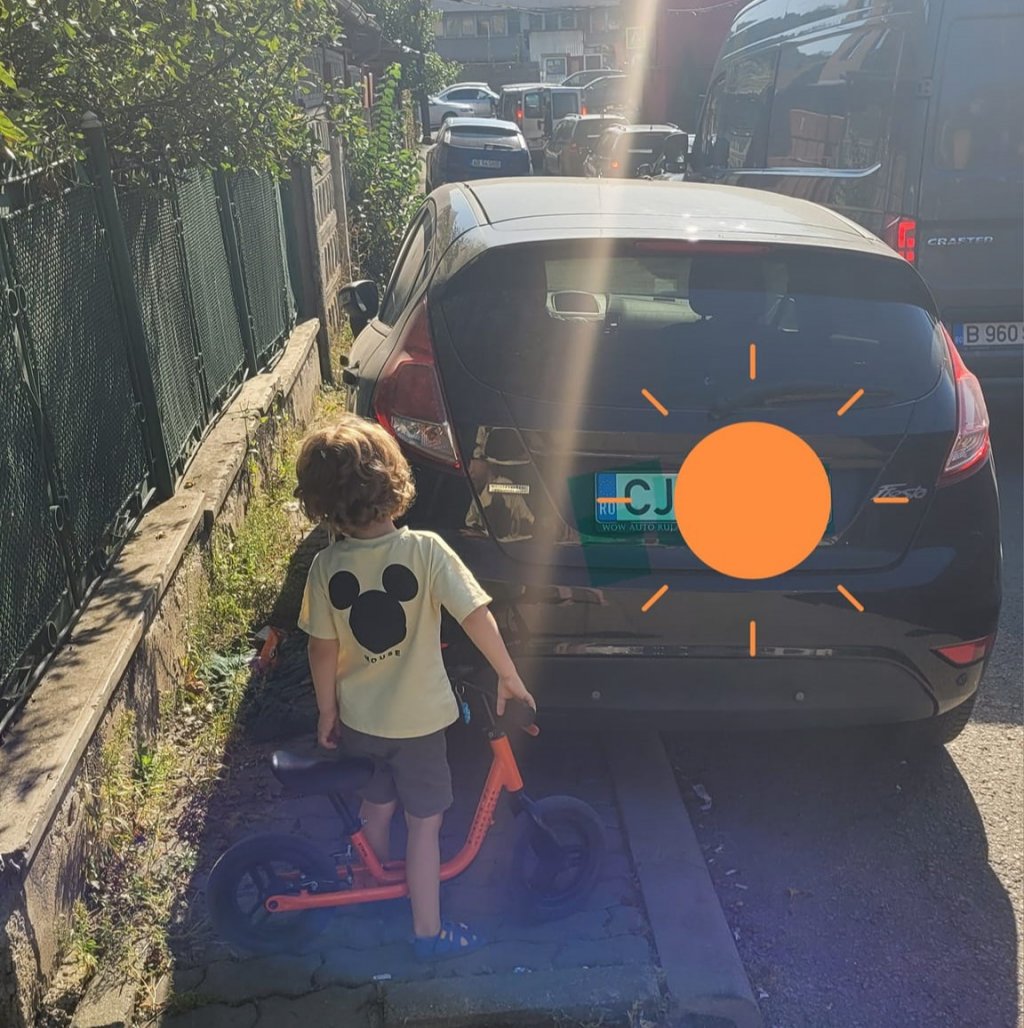 O imagine care reflectă crunta realitate. Mămică din Cluj: “Eu, copilul și bicicleta mergem spre stația de autobuz. Trafic, plin de mașini parcate pe trotuar”